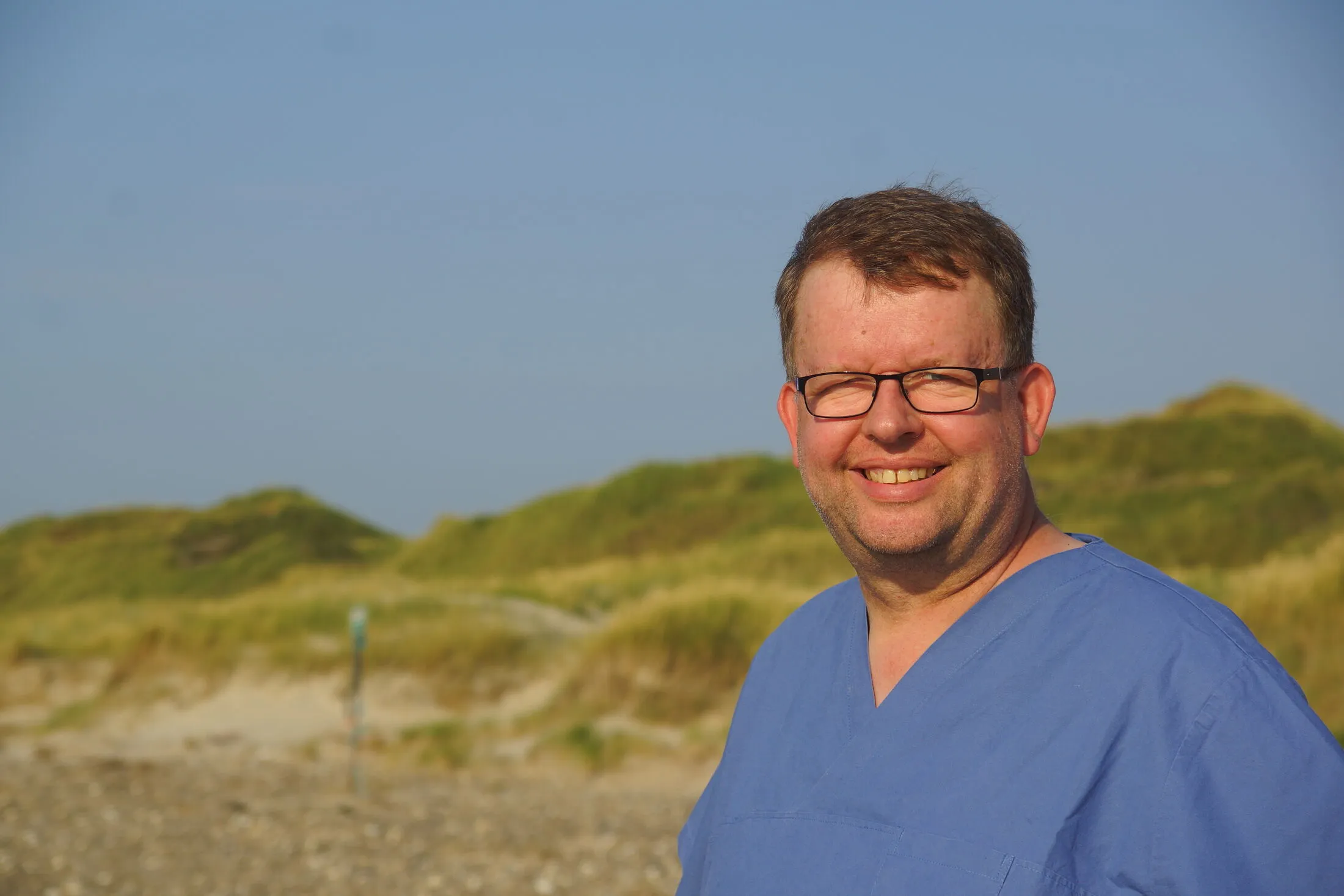 Zahnarzt Tankred Bert Schlicke lächelt in den Dünen